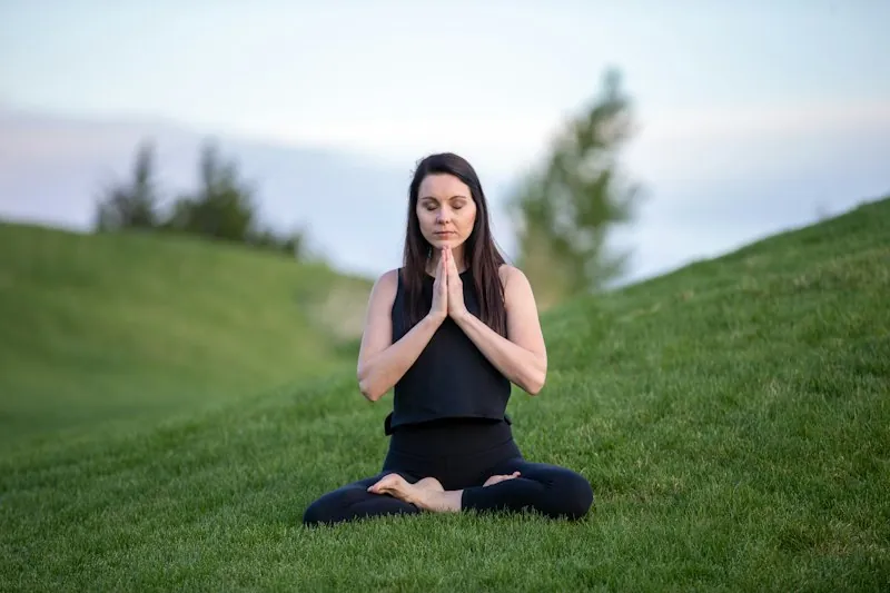 A woman meditating on a grassy field